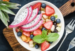 Salada de frutas com pitaya branca fatiada, morango, uva e maçã, exibindo uma mistura vibrante de cores e texturas.
