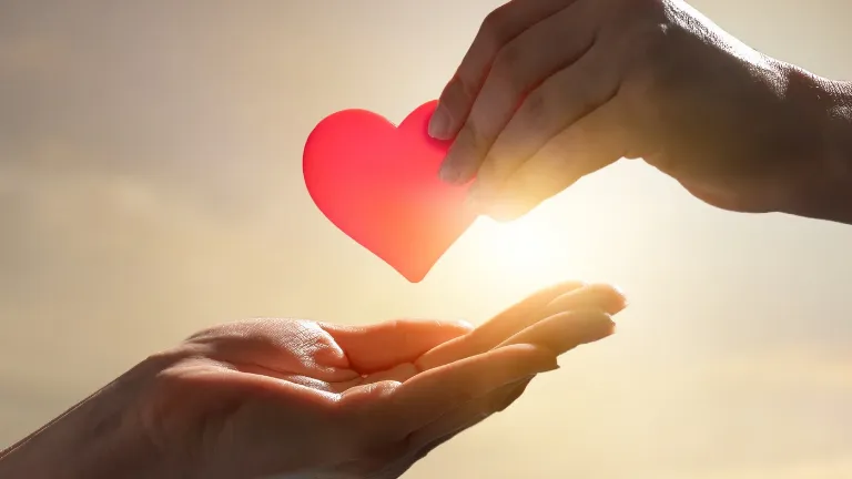 Tu me amas: uma expressão de carinho e generosidade, com uma mão oferecendo um coração à outra, iluminadas pela luz do amor.