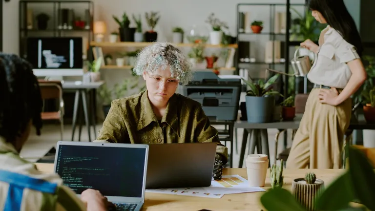 Ambiente de trabalho harmonioso, onde o cuidado mútuo e a presença de plantas reforçam o sentimento de bem-estar e companheirismo.